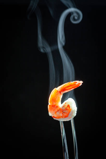 istock shrimp on the fork with dark background. shrimp with steam and smoke on fork close up.selective focus tiger shrimp on silver fork,  food concept 1455711006