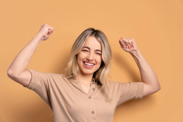 istock woman flexing arms in beige colors. 1455711408