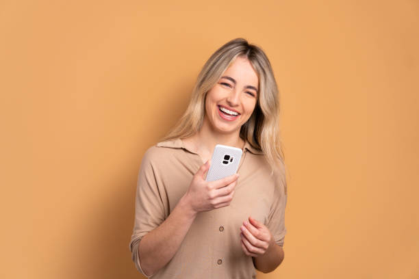 istock fun woman smiling and holding mobile phone 1455711705