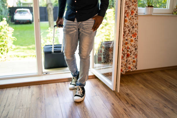 istock Unrecognizable man walking through the patio doors of his rental accommodation pulling a wheeled suitcase 1455712247