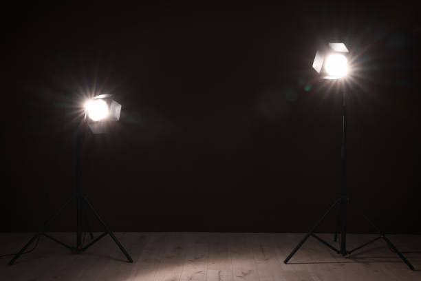 istock Bright spotlights near wall in dark room, space for text 1455714217