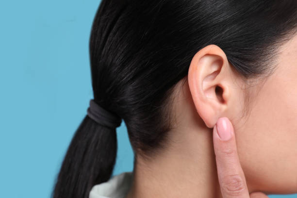 istock Woman pointing at her ear on light blue background, closeup 1455714308