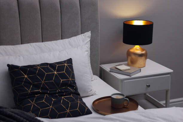 istock Stylish lamp and book on bedside table indoors. Bedroom interior element 1455715478