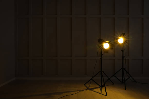 istock Bright yellow spotlights near wall in dark room, space for text 1455716456