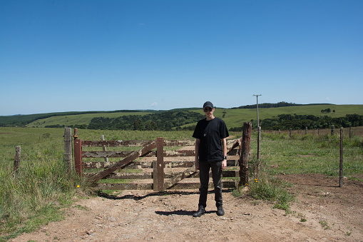 Man in black clothing standing in front of a doorway with the field in the background in brazil
