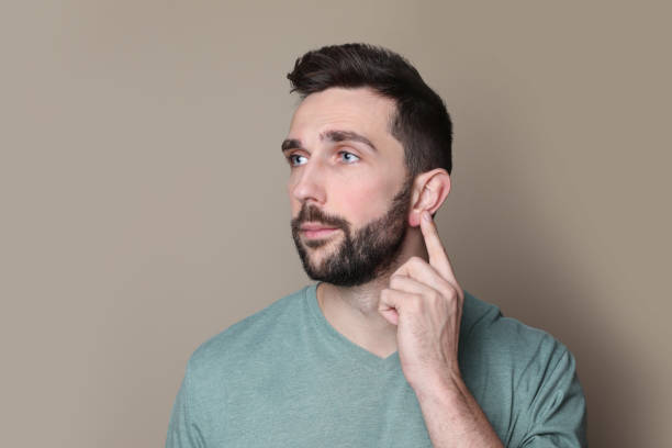 istock Man pointing at his ear on grey background 1455717231