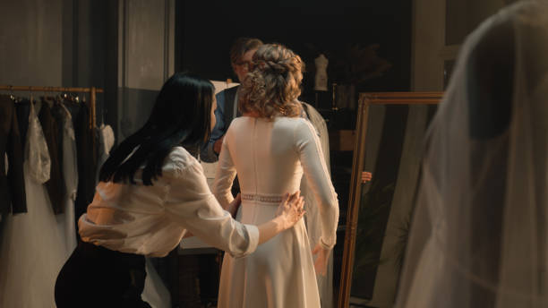 Tailor zips up wedding dress on woman