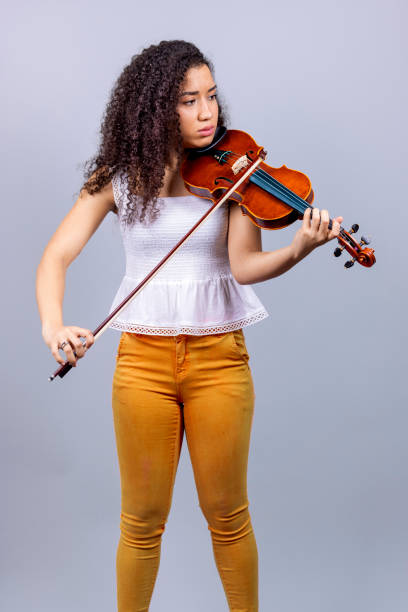 istock Beautiful young woman playing violin over gray 1455720392