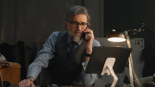 istock Mature tailor talking by phone in atelier 1455721732