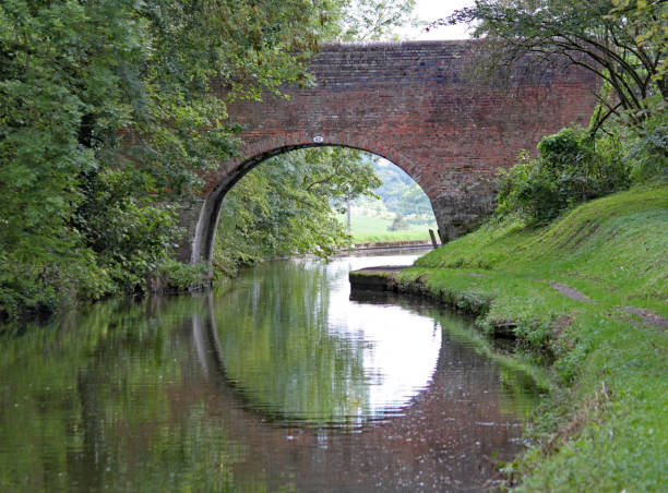 uma ponte arqueada no canal grand union em lapworth em warwickshire, inglaterra - warwickshire narrow nautical vessel barge - fotografias e filmes do acervo