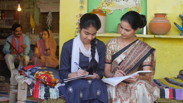 A female teacher with a village teenage girl - sitting on a Chaarpai, home education, Shiksha, Beti bachao Beti padao