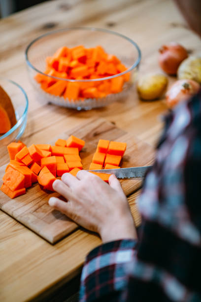 istock Young Woman Chops Pumpkin For Soup 1455723617
