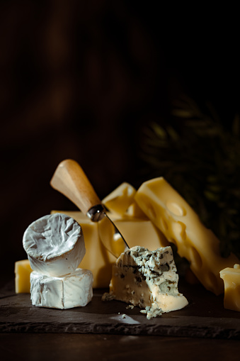 Cheese variety, many different types of cheeses on black background.