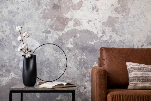 istock Modern composition of living room interior with brown sofa, stripes pillow, square coffee table, dark vase with dried flowers, book and pillows. Home decor. Template. 1455723879