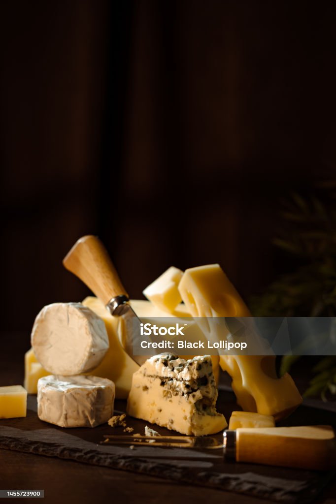 Cheese plate on dark background. Cheese variety, many different types of cheeses on black background. Cheese Stock Photo