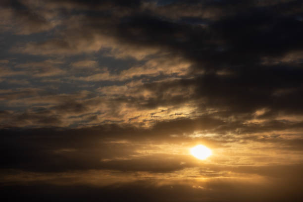 istock Beautiful golden sunset shining through the sky with clouds all around it 1455725352