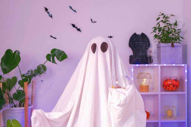 istock ghost eats Halloween sweets. A ghost eats worms, candy, sweets or muck, purse or life. Merry Halloween. 1455728171