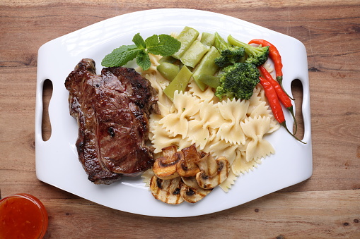Flat lay of grilled steak served with frird vegetables and garlic sauce