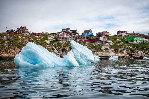 icebergs floating in front of Ilulissat village with colourful houses, View from a boat, Greenland
