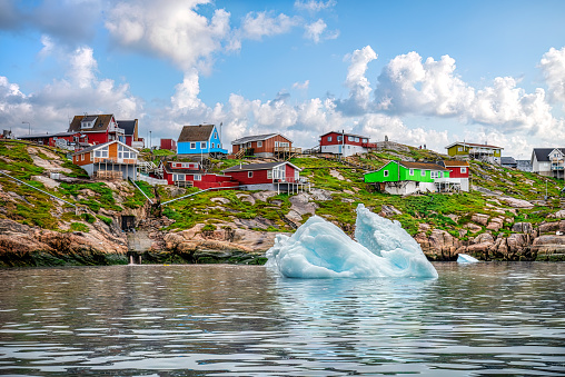 icebergs floating in front of Ilulissat village with colourful houses, View from a boat, Greenland