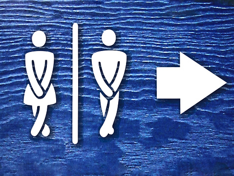 public toilet sign board with white woman and man figure and arrow on blue background or surface. public toilet or wc sign board photo with copy space