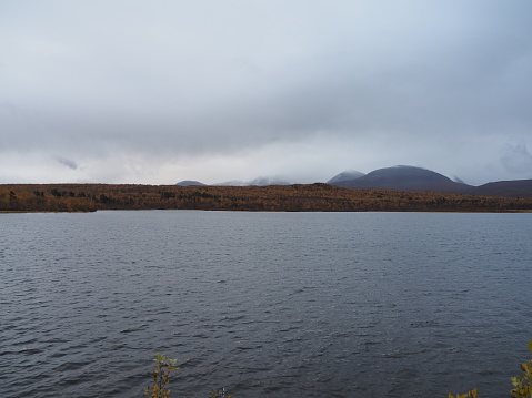 Landscape picture of a lake in Abisko National Park, the Swedish part of Lapland in the colorful autumn season with snow covered mountains in the background.