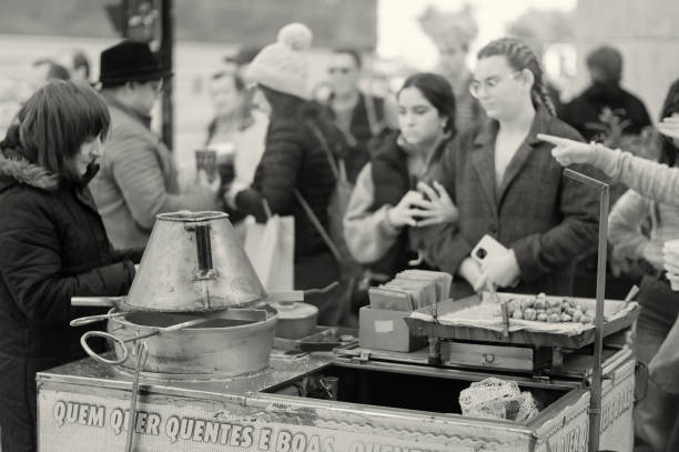 Lisbon, Portugal - November 19, 2022: A traditional roasted chestnuts vendor attends a client in Lisbon downotown.
