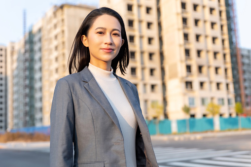 Confident beautiful Asian businesswoman standing in front of resident buildings