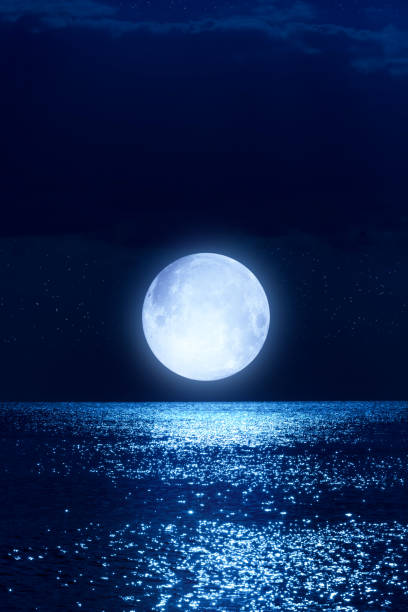 istock Full Moon with starry skies rising above ocean horizon. 1455741984