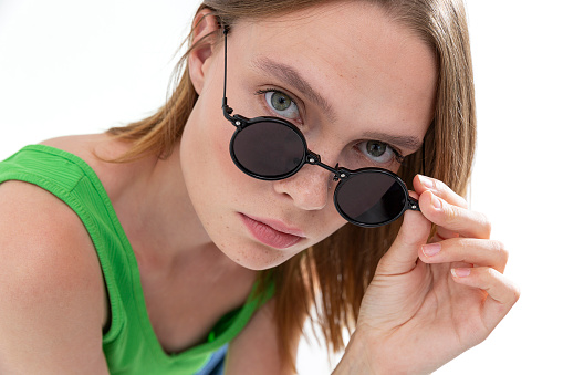 Blonde freckled girl wearing sunglasses. Photo studio with sunlight.