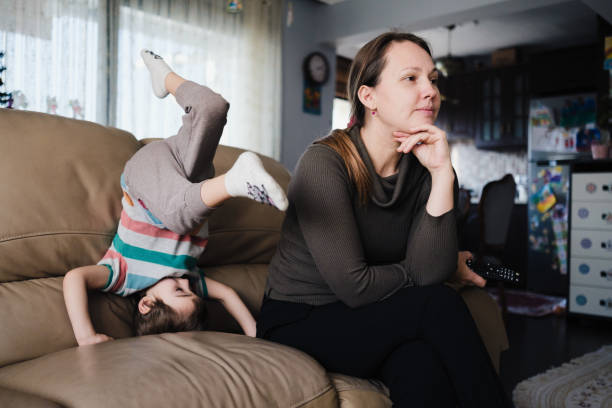 Little child boy distracts mother from watching TV and having some rest