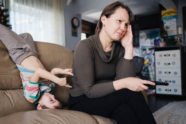 istock Little child boy distracts mother from watching TV and having some rest 1455746949