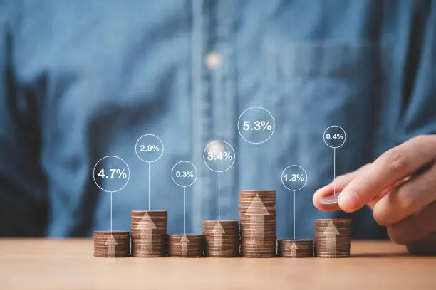 Photo of Businessman stacking coins in different height with percentage for interest rating from differ investment , Financial profit return and dividend concept.