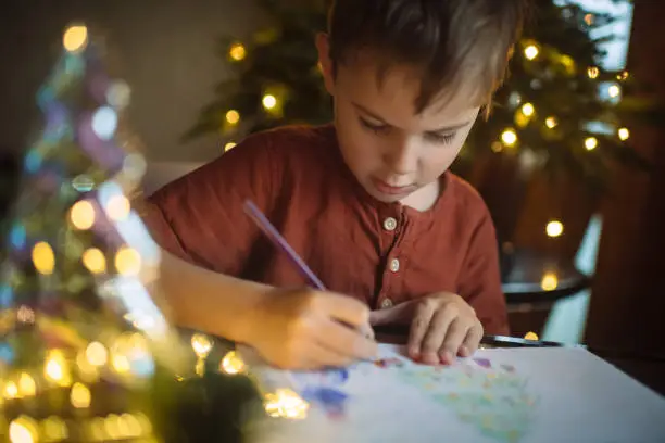 Photo of Little boy drawing a picture for mom and dad for Christmas