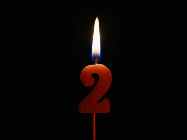 istock Burning birthday candle isolated on black background, number 2 1455749321