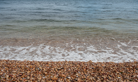 Sea background with pebbles and splash of water wave foam