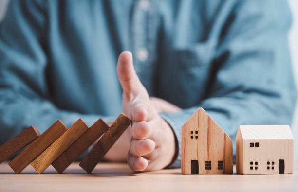 Businessman hand protect and stop wooden house from domino falling wooden bar for risk management and analysis of real estate concept. Businessman hand protect and stop wooden house from domino falling wooden bar for risk management and analysis of real estate concept. oops stock pictures, royalty-free photos & images