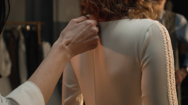 istock Tailor zips up wedding dress on woman 1455753435