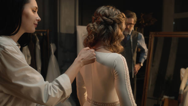 istock Tailor zips up wedding dress on woman 1455753468