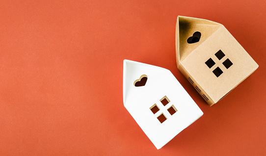 White and Brown paper house origami on red background with empty space for your text or message.