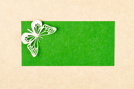 A Butterfly made from carve paper or cutting on green and yellow background with empty space for your text or message.