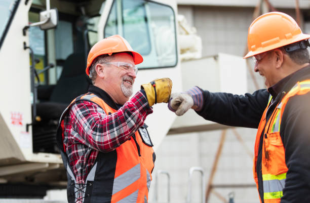 istock Two construction workers by crane, fist bump 1455754027