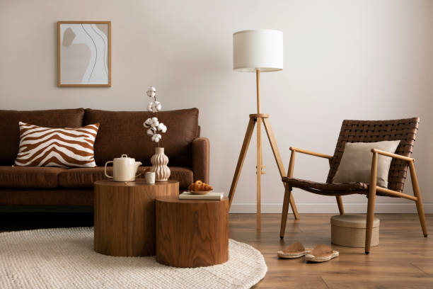 design intérieur de la chambre élégante et élégante avec canapé marron, fauteuil en rotin, tables basses en bois, théière, maquette cadre d’affiche, décoration et accessoires personnels. décoration chaleureuse de la maison. modèle. - designer living room brown white photos et images de collection