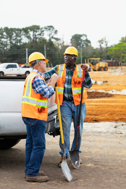 istock Construction workers with shovels converse by pickup truck 1455755084