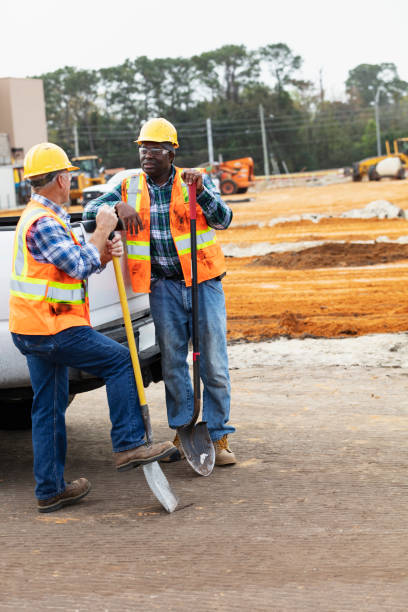 istock Construction workers with shovels converse by pickup truck 1455755086