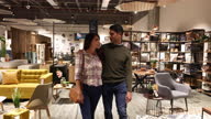 istock Happy heterosexual couple walking through a furniture store looking at the different showcases while talking and smiling 1455756377