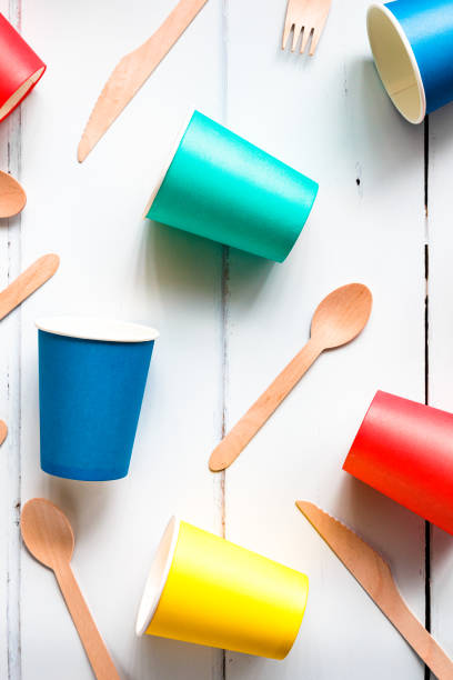 Colorful recyclable paper cups and wooden kitchenware utensils on white background