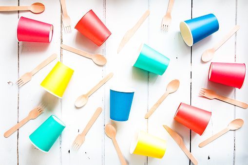 Colorful recyclable paper cups and wooden kitchenware utensils on white background