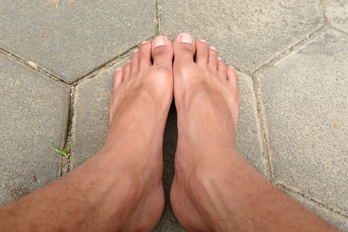 adult men's feet on paving blocks without shoes