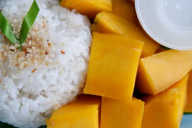 Mango sticky rice , dessert made with glutinous rice, fresh mango and coconut milk, and eaten with a spoon or the hands.